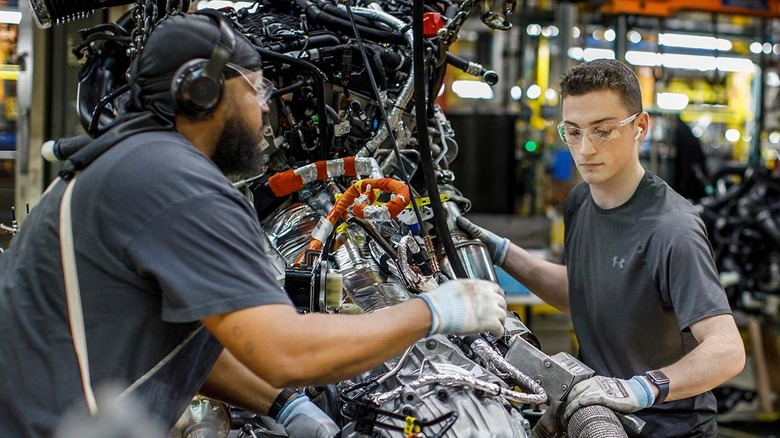 Two factory workers working on Ford engines