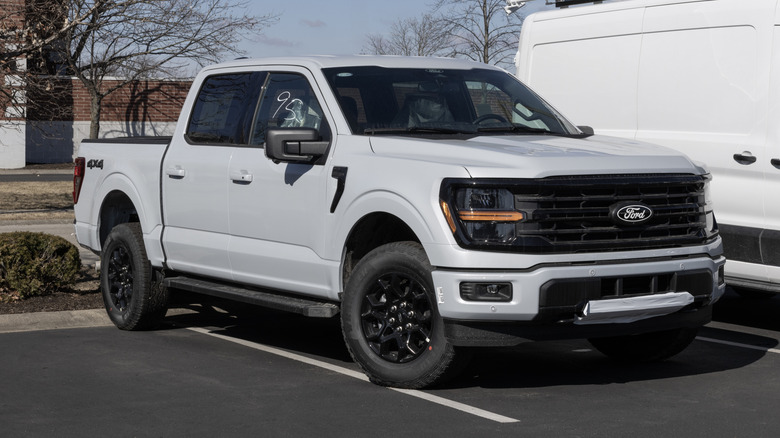 A new Ford F-150 in gray on display at a dealership, front 3/4 view