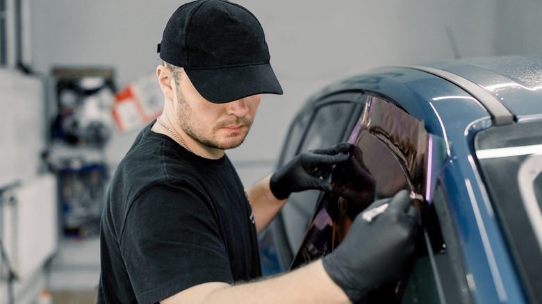 A person applying tint to the front passenger window