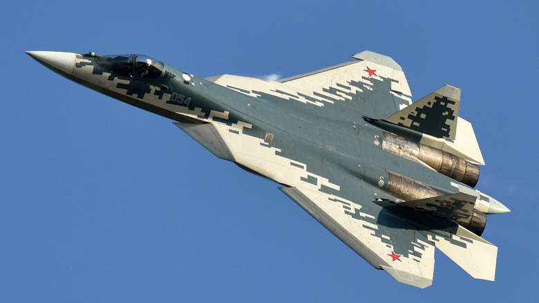 A Su-57 fighter jet in mid-flight with a sky background