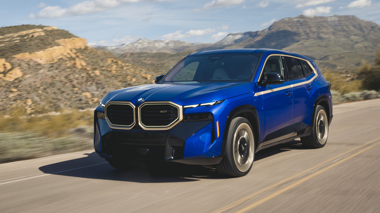 2023 BMW XM in blue with gold trim driving through mountains