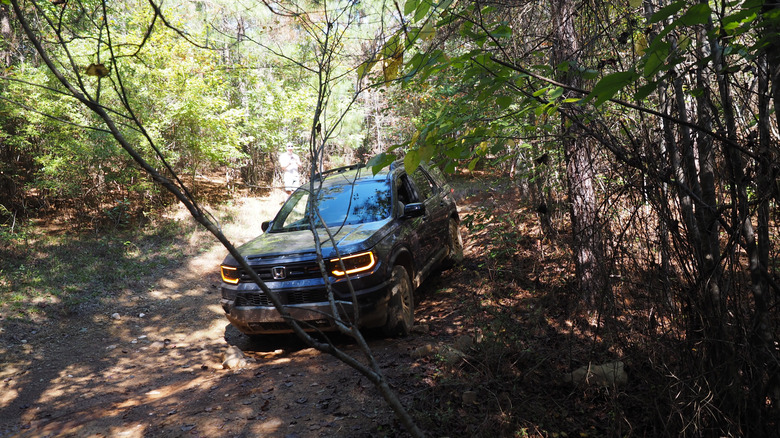 2027 Honda Passport Trailsport traversing over a forest trail