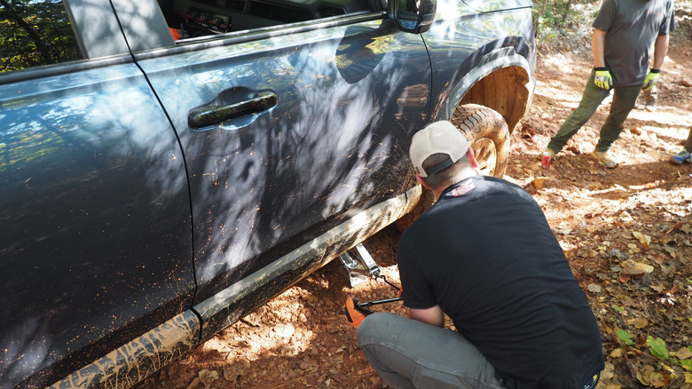 A Honda engineer jacks up 2027 Honda Passport TrailSport to replace a flat tire on the trail