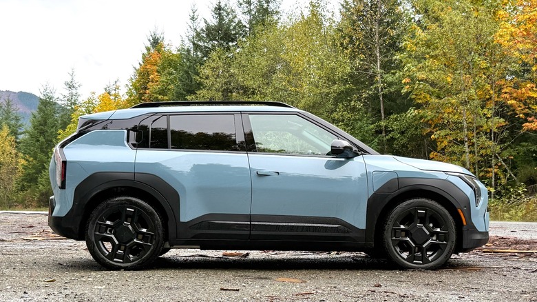 2027 Kia EV3 parked in a forest with changing colors on the leaves