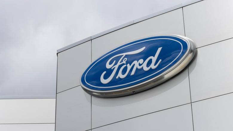 The iconic blue and white Ford logo on the side of a silver warehouse.