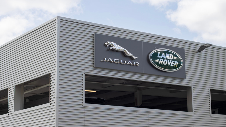 The Jaguar and Land Rover logos next to each other on the side of a grey industrial-looking building.