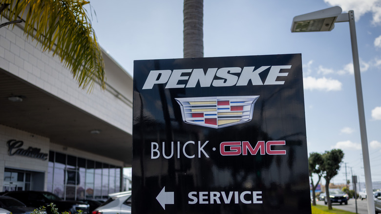 The GMC, Buick, and Cadillac logos all mounted on a black pillar outside a service center.