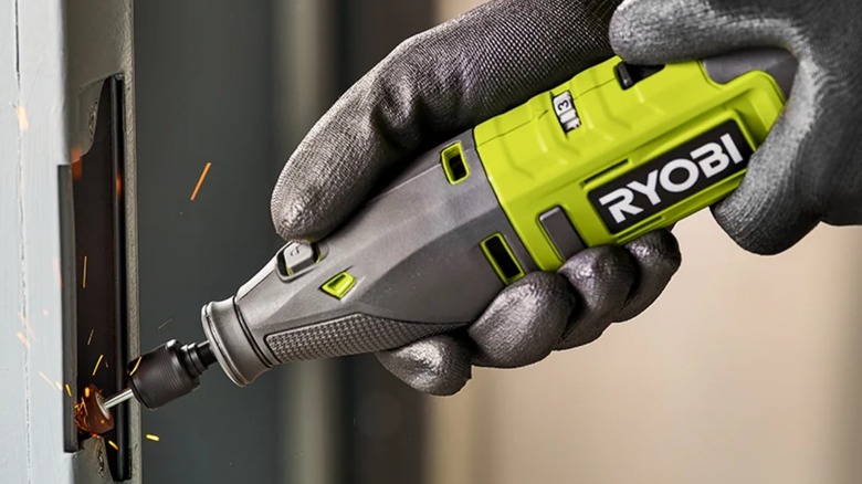 A person using a Ryobi rotary tool on metal.