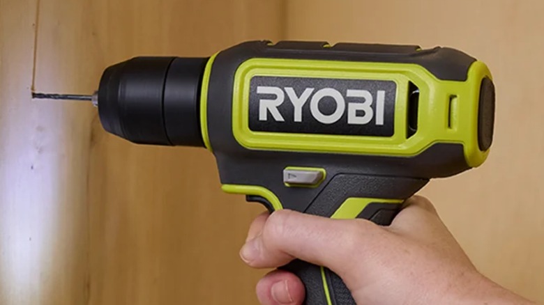 A person using a Ryobi cordless drill on wood.