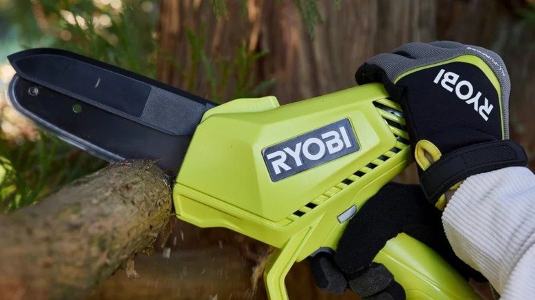 A person using a Ryobi pruning chainsaw on a tree.