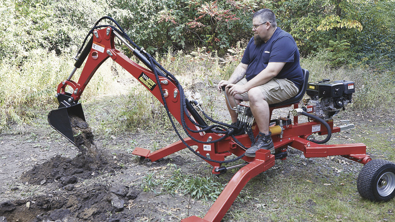 A man using the NorTrac towable backhoe trencher
