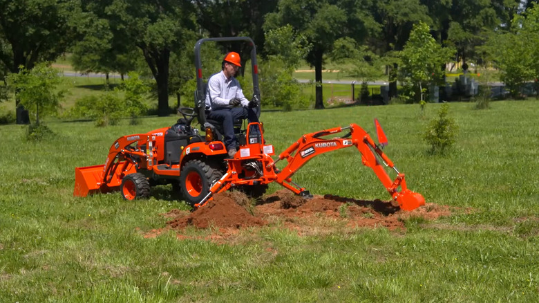A person using the Kubota Tractor Loader Backhoe in a field