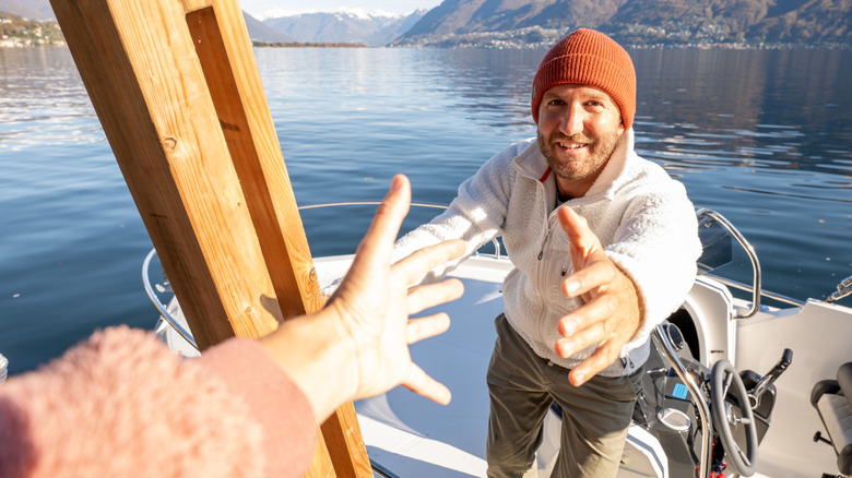 Close-up of man taking another person's hand to disembark from boat.