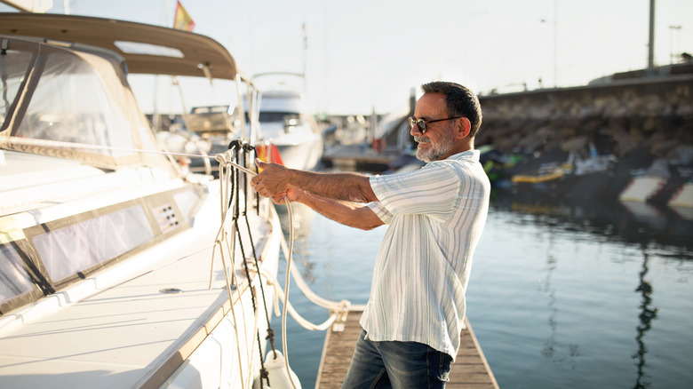 Man securing boat to dock.