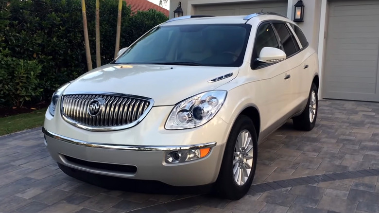 A white 2011 Buick Enclave parked in front of a residential garage