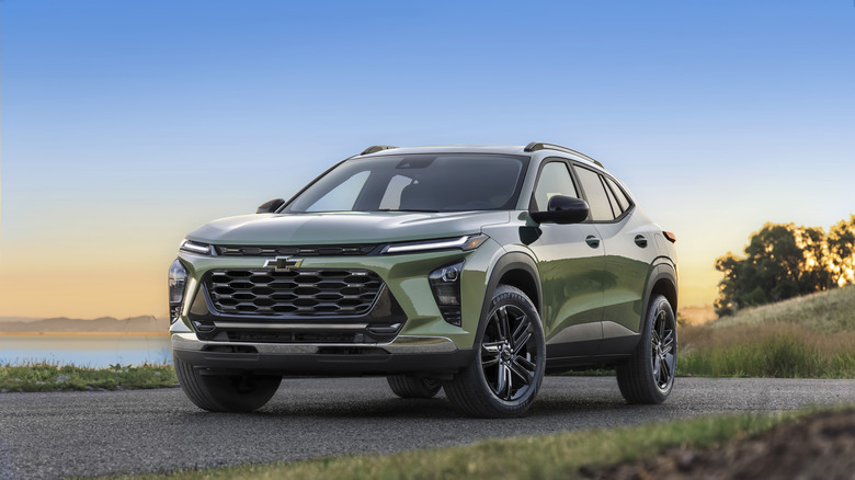 A green 2026 Chevrolet Trax parked at sunset on a paved road near water