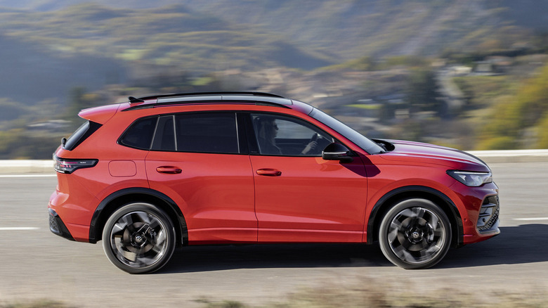 A bright red Volkswagen Tiguan on the road with mountains in the background