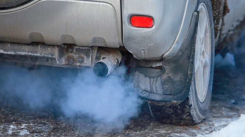 Rear 3/4 view of car with blue exhaust smoke