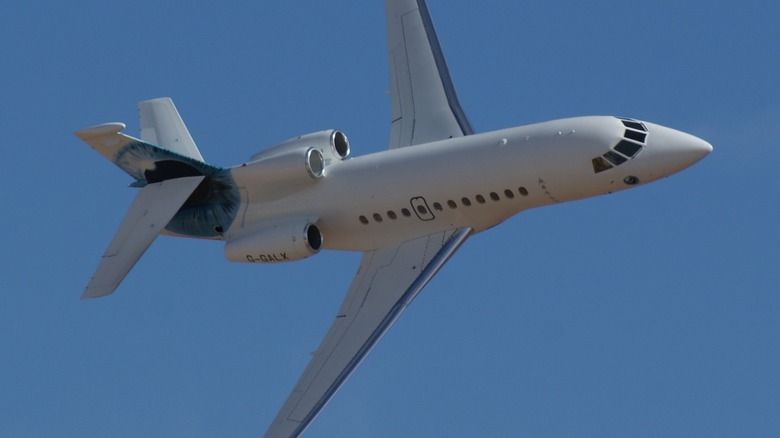 A Falcon 900EX flying over a cloudless blue sky