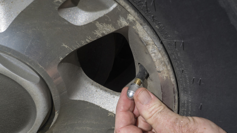 A close-up of a hand putting on a new valve stem cover on a tire's valve stem