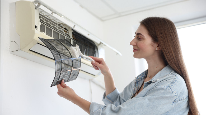 A woman cleaning a split air conditioner filter