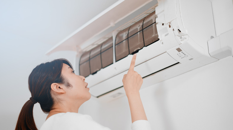 A woman looking at a wall-mounted air conditioning unit
