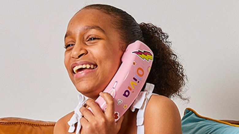 A young girl using a pink Ooma MyPhone with stickers on it