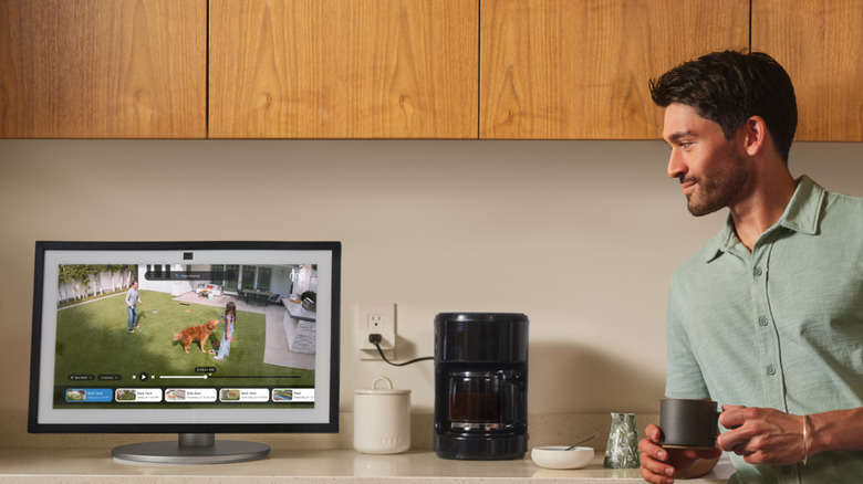 A person having a coffee and watching a live camera feed on an Echo device