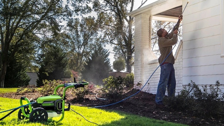 Using the Greenworks electric pressure washer to clean siding on a house.