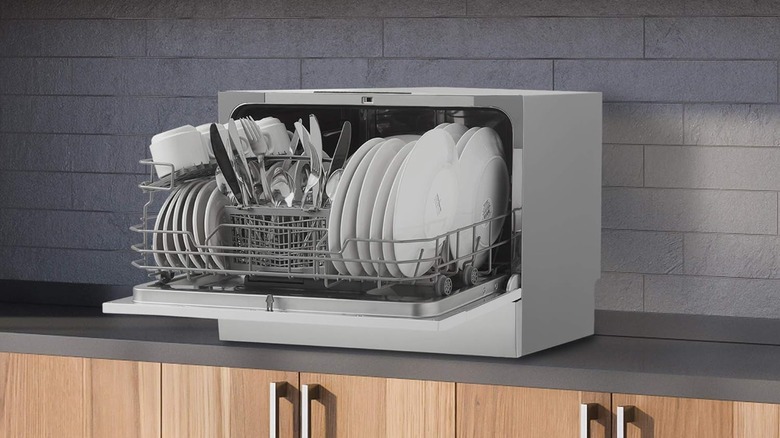 A Danby countertop dishwasher sitting open with clean dishes on a pulled-out rack