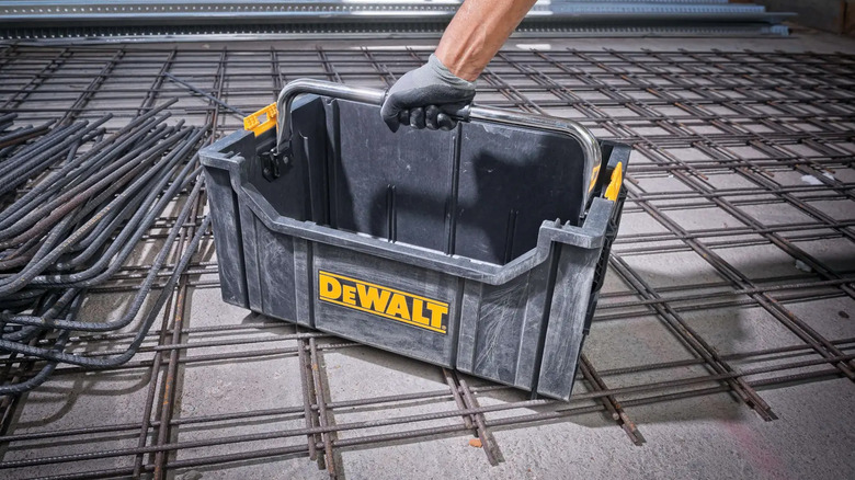 DeWalt's Tote with Carrying Handle on the ground, a hand is on the handle.