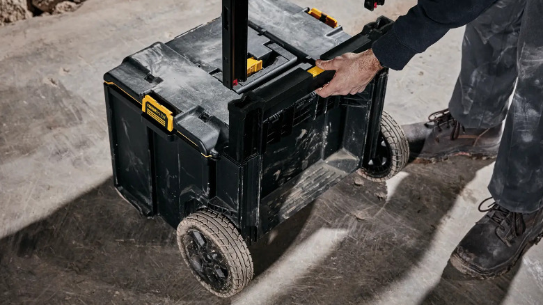 A person removes the handle from the DeWalt rolling toolbox.