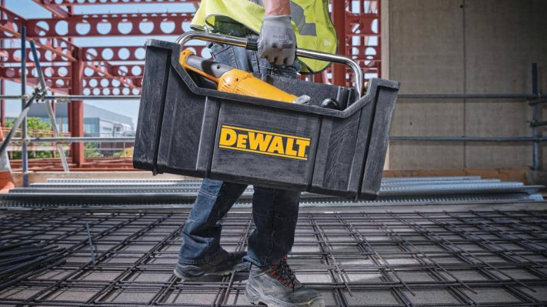 A person carrying the DeWalt Tote with Carrying Handle by the handle.