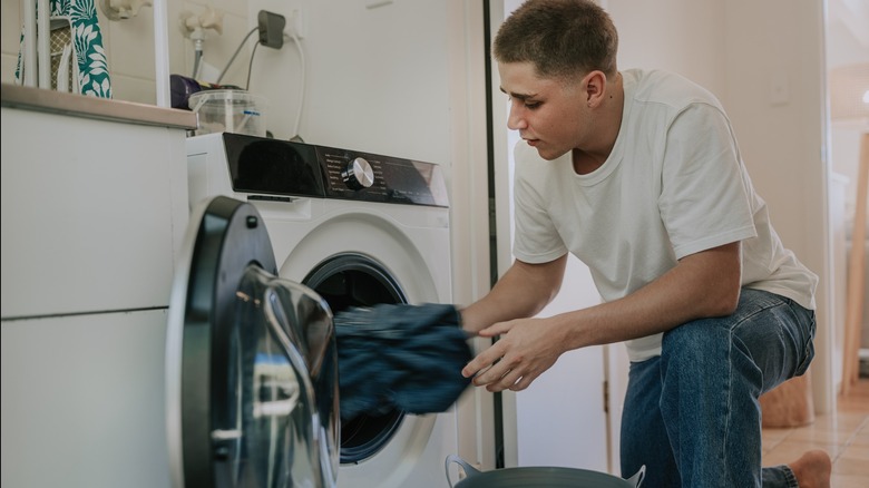 Man crouching to load washing machine