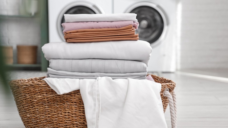 Basket with clean bed sheets in laundry room