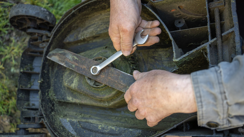 Close-up of person disassembling lawn mower.