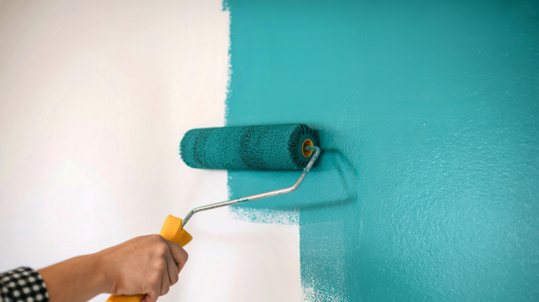 Person painting wall with paint roller