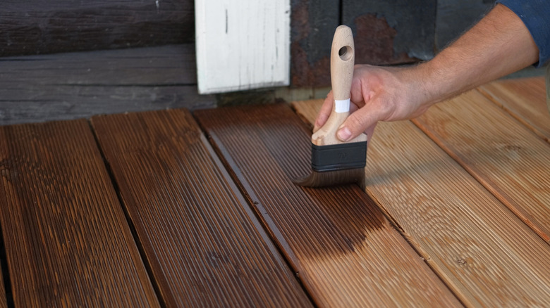 Person applying wood stain with brush