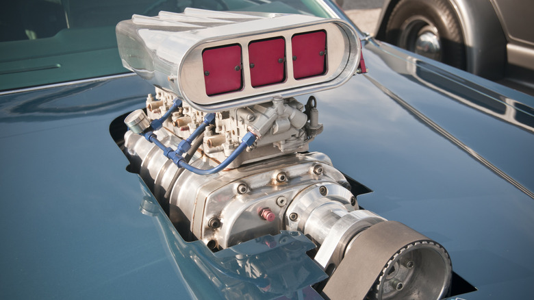 A part of a roots supercharger (a blower) sticking out above the hood of a muscle car