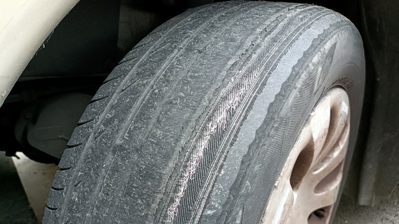 Close-up of a very worn tire on a silver vehicle