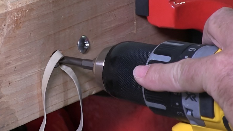 Sticking drill into screw through rubber band 