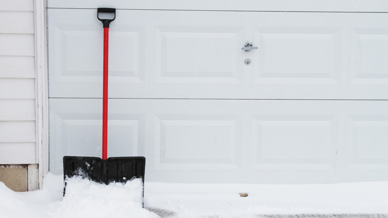 snow shovel leaning up on garage door.