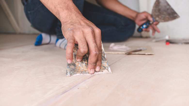 A man filling gaps on a floor