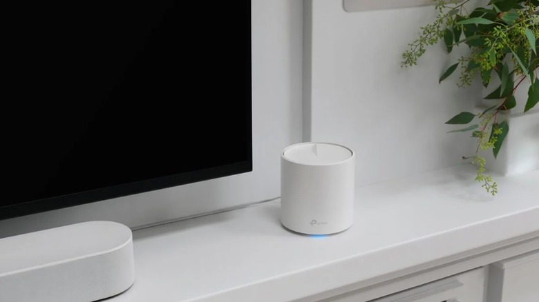TP-Link mesh Wi-Fi router on a modern sideboard next to a TV and soundbar