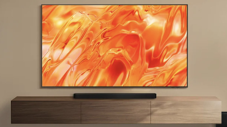 A Samsung TV mounted on a brown wall over a modern entertainment center