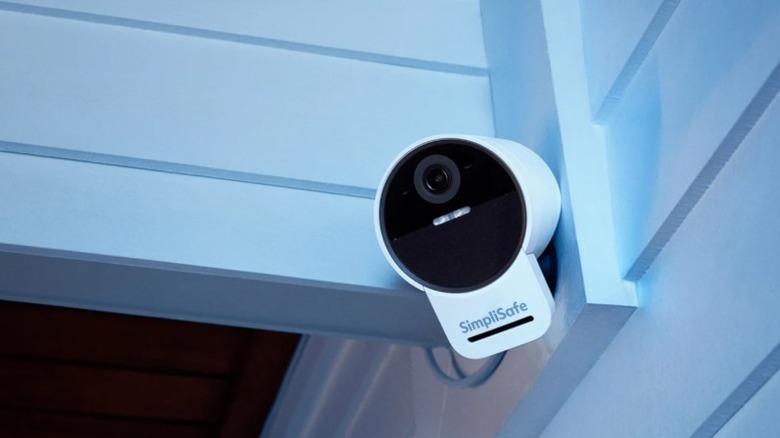 A SimpliSafe outdoor security camera mounted on white siding