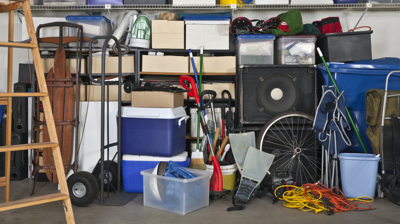 A messy garage space stacked with bins, boxes, bicycles, coolers and more