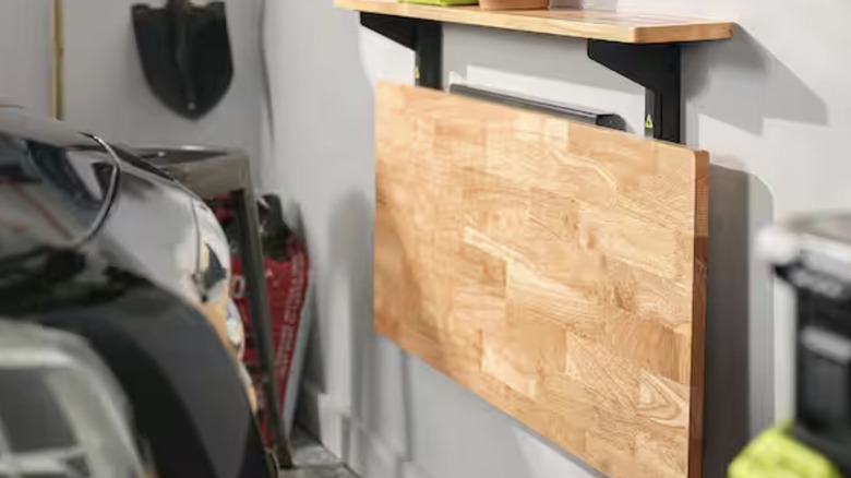 The Ryobi Stowaway Wall Mounted Work Bench installed in a garage with a parked car in front of it