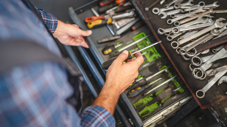 Person examining tools in tool box