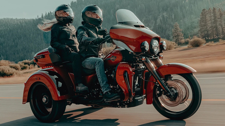 Two bike riders on red Harley-Davidson Tri Glide Ultra